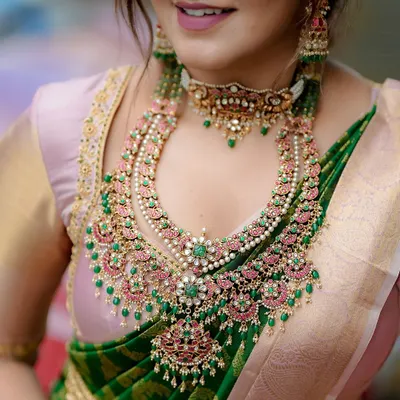 A detailed close-up of a magnificent layered Polki and Kundan bridal set. The combination of pink and green stones with uncut diamonds and pearls creates a breathtakingly grand look.
