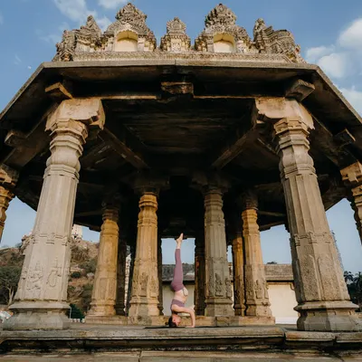 Practicing Pincha Mayurasana (Forearm Stand) inside a historic Indian temple. The stability and focus required for inversions feel amplified in such a powerful, ancient space.