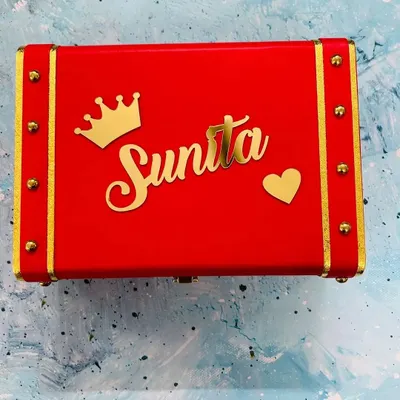 This vibrant red keepsake trunk is personalized with a name, a crown, and a heart charm. The gold accents and hardware give it a luxurious, vintage feel.
