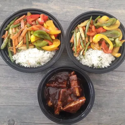 A complete meal prep featuring my no onion, no garlic rice bowls. This shows two bowls with rice and stir-fried vegetables, alongside a separate portion of the flavourful peanut butter tofu.