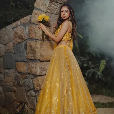 This image captures a dreamy, romantic mood. The soft lighting and natural setting complement the shimmering yellow lehenga, making it ideal for a pre-wedding or festive collection.