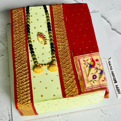 A slice of tradition. This stunning cake is designed to look like a folded Paithani saree, complete with an edible mangalsutra and nath. It's a beautiful tribute to our culture, made entirely from whipped cream and fondant.