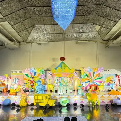 A massive, colorful carnival stage featuring a carousel centerpiece, circus train props, and vibrant backdrops.