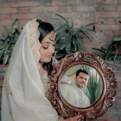A creative and symbolic portrait where the bride, Lubna, holds a mirror reflecting her groom, Wamiq. This shot beautifully represents seeing one's world in their partner.