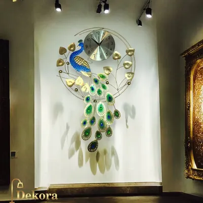 A full view of our metal peacock clock, showcasing the vibrant blue and green details of its cascading tail. It's a handmade statement piece for any large wall.