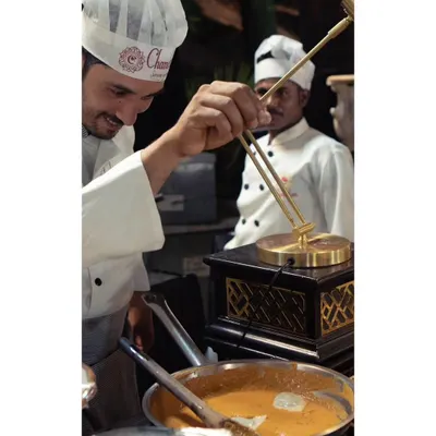 A smiling chef at our live Palak Paneer Ravioli station. The joy he takes in his craft is evident as he prepares this unique fusion dish.