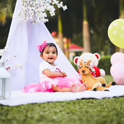 A perfect smile during an outdoor first birthday shoot. I set up a comfortable spot with a teepee, balloons, and teddy bears to create a fun and relaxed environment in the park.