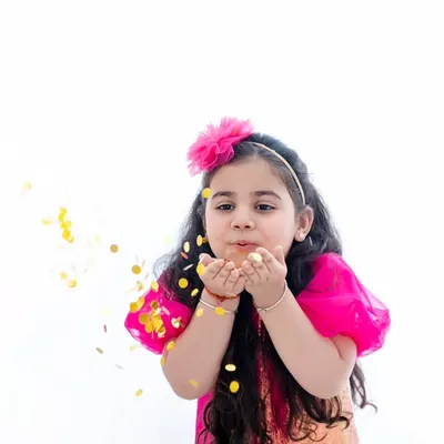 Making a wish. This action shot of a young girl blowing glitter towards the camera is full of magic and movement.