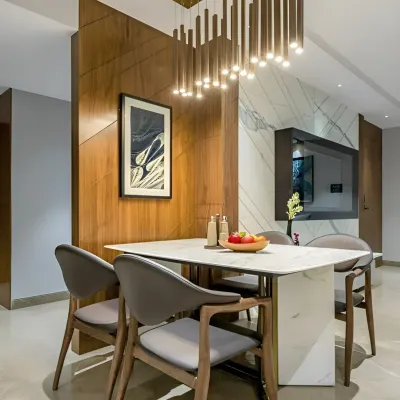A modern dining setup defined by a wooden partition wall that separates it from the living area. The statement pendant light fixture and marble-top table create an elegant space for family meals.