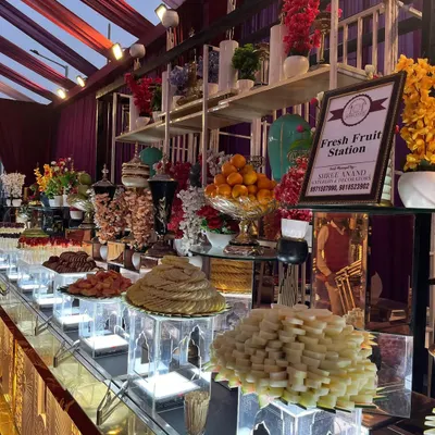 A beautifully arranged fresh fruit station is a healthy and colorful addition to any event. This display features a variety of seasonal fruits, from whole oranges to sliced kiwis and dates on skewers, all presented artfully.
