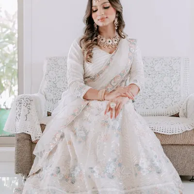 A vision in white. This bride looks absolutely angelic in an ivory lehenga, paired with a stunning Kundan and pearl necklace set. This is a perfect look for a serene daytime ceremony.