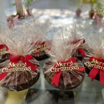 A close-up of my festive Christmas cakes, ready for corporate gifting. Each cake is individually wrapped and finished with a red ribbon and "Merry Christmas" tag for a polished, professional gift.