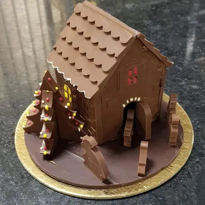 This fully edible chocolate Christmas hut is a centerpiece for any holiday celebration, handcrafted with intricate details from luxury milk chocolate.
