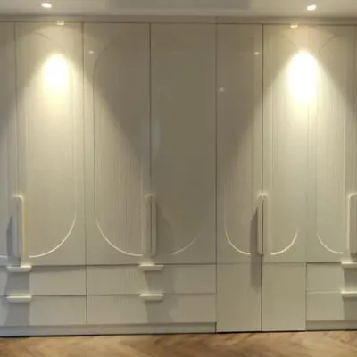 This floor-to-ceiling wardrobe in a high-gloss PU finish showcases our precision craftsmanship. The custom CNC-milled design adds a unique, artistic touch to the bedroom.