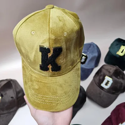 A close-up of our custom suede cap, showing the textured fabric and the detailed sequin initial patch.