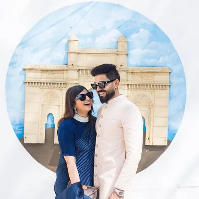 A candid, laughing moment in front of a Gateway of India mural. This shot captures the fun, urban vibe of a Mumbai pre-wedding shoot.