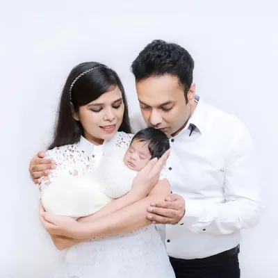 A tender moment with new parents cradling their sleeping newborn. The all-white theme gives this first family portrait a pure and serene quality.