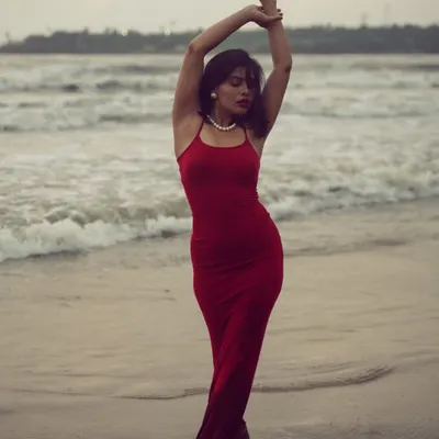A full-length portrait of a model in a red dress against the waves. This shot is about capturing graceful movement and the powerful contrast between the subject and the sea.