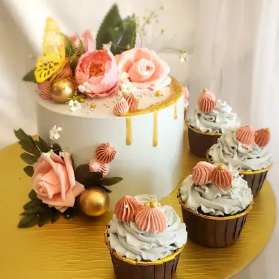 This elegant floral drip cake is paired with matching cupcakes. Decorated with delicate sugar flowers, a golden drip, and a butterfly, it's perfect for a special celebration like Valentine's Day or an office anniversary.