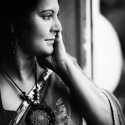A contemplative black and white profile, where the subject gazes thoughtfully out of the frame. The soft light traces the lines of her face and hand, highlighting a moment of quiet introspection.
