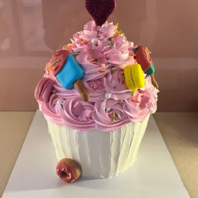 Why have a cupcake when you can have a giant cupcake cake? This fun design is frosted with pink buttercream and decorated with tiny edible macarons and popsicles for a super sweet celebration.