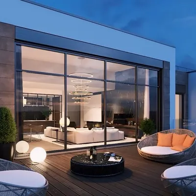 An exterior view of a modern terrace lounge, showing the structure's clean lines and integration with the building. The open deck features comfortable seating, perfect for enjoying the evening air.