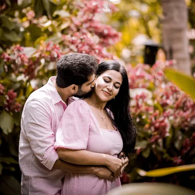 A romantic kiss in the garden, surrounded by beautiful pink flowers. A perfect, intimate moment for a pre-wedding shoot.