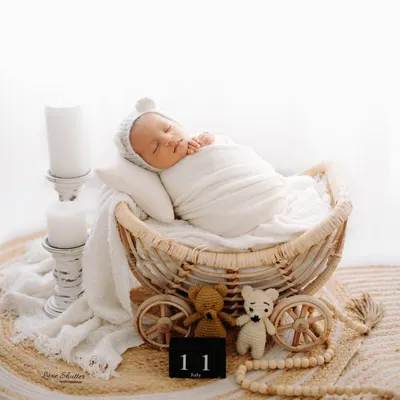 A peaceful 11-day-old newborn sleeping in a rustic wicker pram. We use a variety of props and soft, neutral tones to create these timeless newborn portraits.