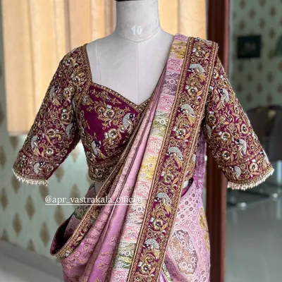 A breathtaking bridal blouse in magenta, completely covered in intricate zardosi and threadwork. The design features peacock and floral motifs, perfect for a grand wedding ceremony.