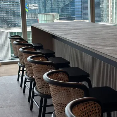 A row of my custom-made bar stools with cane backs and black frames, installed at a corporate office bar in a high-rise with a city view.