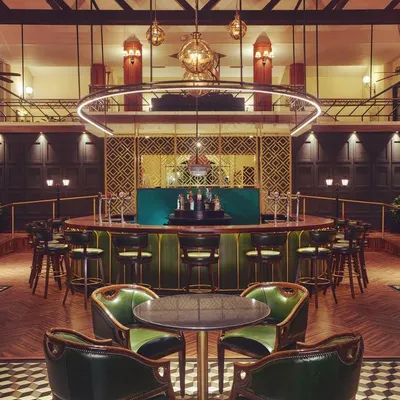 A head-on view of the Double Eagle Bar at KGA, where the lighting design balances drama and comfort. The circular fixture provides functional light over the bar while accent lights define the seating areas, creating an inviting space for patrons.