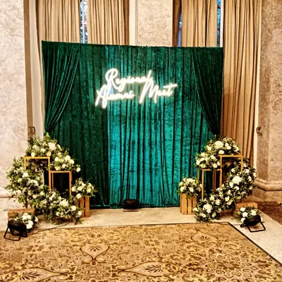 This is the 'Regional Alumni Meet' setup in natural light. The rich green velvet backdrop and classic white floral arrangements look just as impressive without special lighting, showing the quality of the materials.