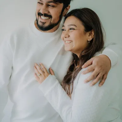 A simple, happy moment from a casual at-home shoot. The coordinated white sweaters and jeans create a clean, timeless look, while their genuine smiles radiate warmth and affection.