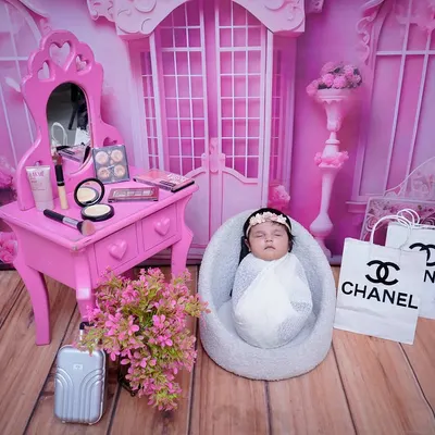 A fashion-forward newborn shoot with a pink Chanel-inspired theme. This setup includes a miniature vanity, designer shopping bags, and a floral backdrop for a truly glamorous first portrait.