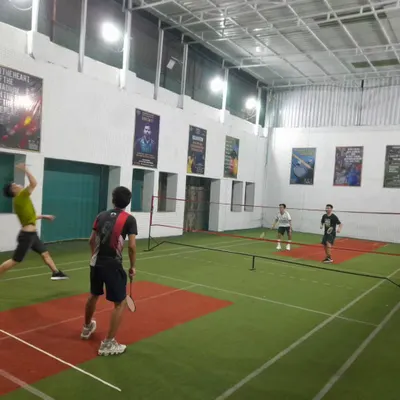 That jump smash moment! A player in mid-air, ready to unleash a powerful shot in a doubles rally.