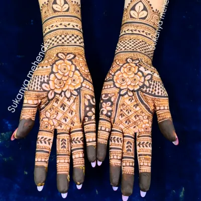 A classic engagement mehendi with bold floral patterns at the center, complemented by delicate lattice work on the fingers and a beautiful cuff design on the wrist.