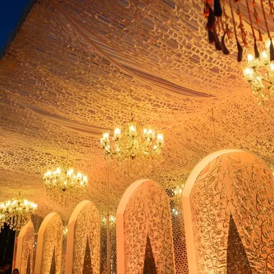 An opulent wedding setup with intricate ceiling drapery and sparkling crystal chandeliers. This image showcases our ability to cater to grand, luxurious events where every detail exudes elegance.