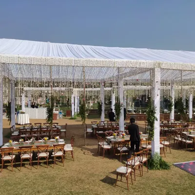 A wide view of a large German hanger tent set up for a day event, showing the scale of the structure and the organized seating arrangement with wooden cross-back chairs.