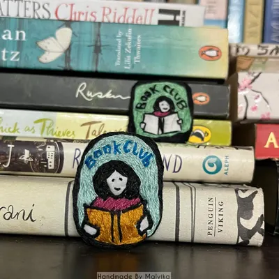 Here is another look at my 'Book Club' badges, resting on a stack of novels. I designed these hand-embroidered accessories to be little conversation starters for anyone who loves getting lost in a good story.