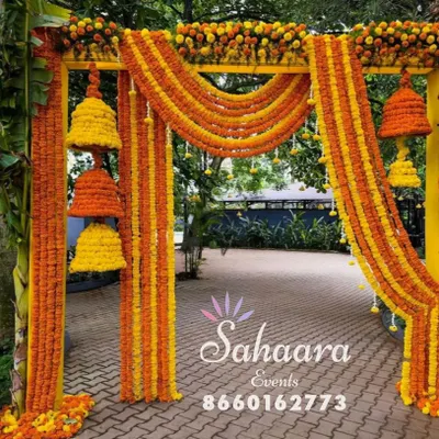 A stunning entrance for a Haldi ceremony. This arch is decorated with bright orange and yellow marigold garlands and hanging floral bells, creating a festive and traditional welcome for guests.