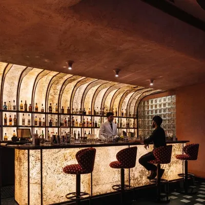 The bar at Idylll restaurant is designed as a glowing monolith. The backlit, textured facade creates a warm and inviting focal point, drawing guests into the heart of the space.