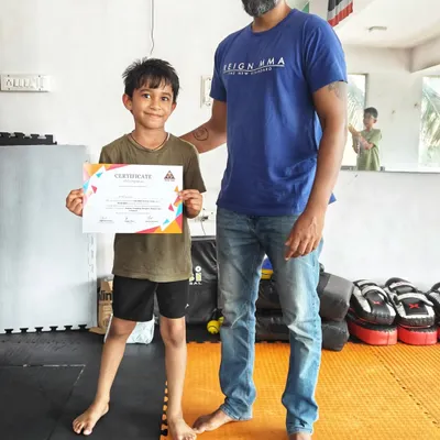 Another proud graduate of our kids' MMA summer camp receiving his certificate from the head coach. We make sure every child's effort is recognized and celebrated.