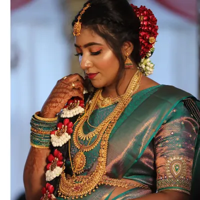 A detailed view of a classic South Indian bridal braid. It is adorned with traditional red and white flowers, creating a beautiful and customary hairstyle that pairs perfectly with a silk saree.