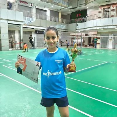 A proud moment for our academy. One of our junior players from the kids' badminton training camp holding her winner's trophy and certificate of achievement.