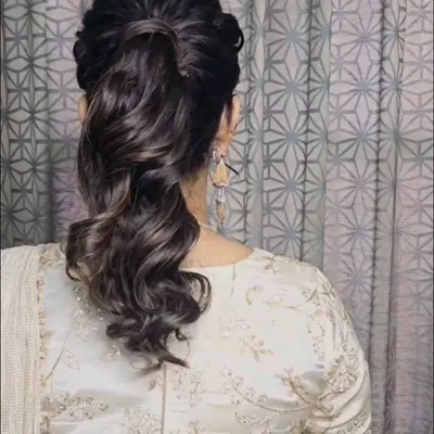 A chic and voluminous ponytail hairstyle. This is a great option for a modern yet elegant look, perfect for a reception or cocktail party.