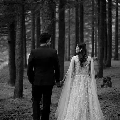 A timeless black and white shot of the couple walking hand-in-hand away into the dense forest, symbolizing the start of their journey together.