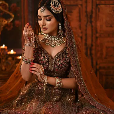 A masterpiece of bridal artistry. This bride's maroon velvet lehenga is paired with dramatic smokey eyes, contoured cheeks, and intricate jewelry for a look that is both royal and captivating.