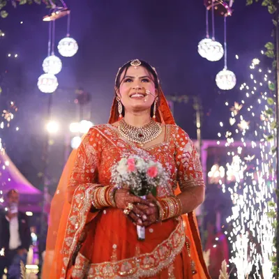 A bride's entry is a showstopper. Here, she walks in with a beautiful bouquet, her path lit by sparklers, creating a truly cinematic and unforgettable moment.