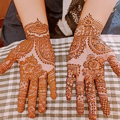 This photo shows a traditional floral and paisley mehendi design on both palms, freshly applied with my organic henna paste. At this stage, the paste is on the skin, and you can see the intricate details before it is scraped off to reveal the initial stain.