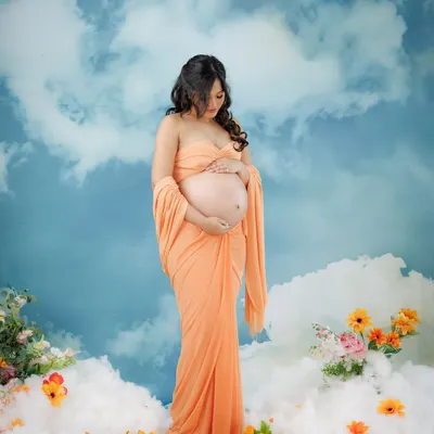 A goddess in the clouds. This dreamy setup, with a peachy fabric drape against a sky backdrop, creates an ethereal and heavenly portrait for the mother-to-be.